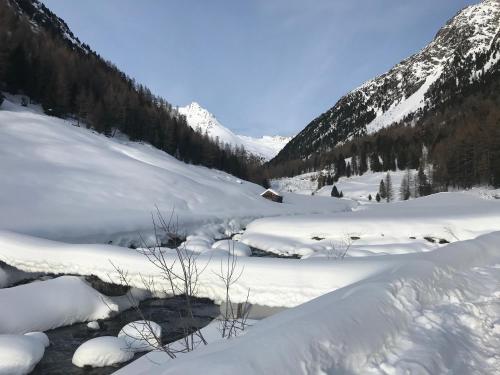 a snow covered mountain with a stream in the foreground at Berghof Niederthai in Niederthai