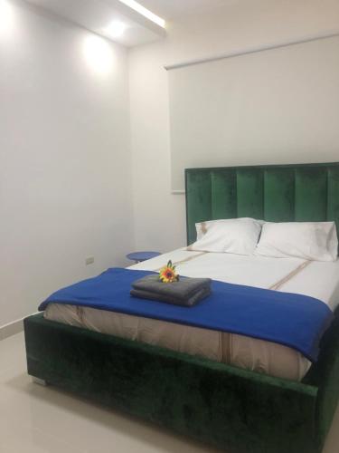 a bedroom with a large bed with a green headboard at Verdana Rental Residencial Arlene II SFM in San Francisco de Macorís