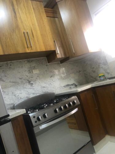 a kitchen with a stove and wooden cabinets at Verdana Rental Residencial Arlene II SFM in San Francisco de Macorís