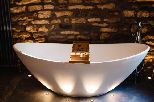 a bath tub in a room with a brick wall at Quite Simply French in Lancaster