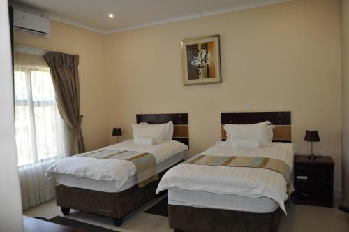 a hotel room with two beds and a window at Bannerloft Guest house in Gaborone