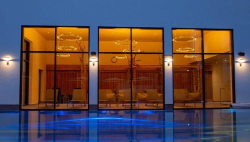 a building with glass windows and a pool at Aktivhotel Waldhof in Oetz