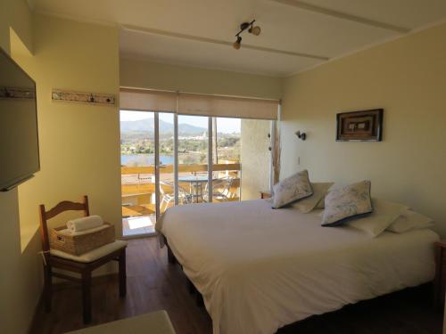 1 dormitorio con 1 cama grande y balcón en Riomar Apart Hotel, en Concón