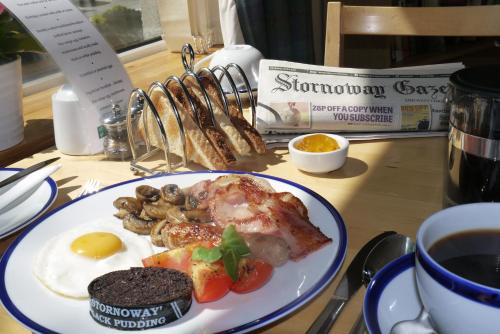a plate of food with eggs and mushrooms and a cup of coffee at Jannel Bed & Breakfast in Stornoway
