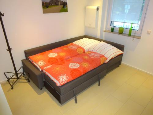a bed in a room with an orange blanket at 2-Zimmer-Ferienwohnung im Herzen von Nordkirchen in Nordkirchen