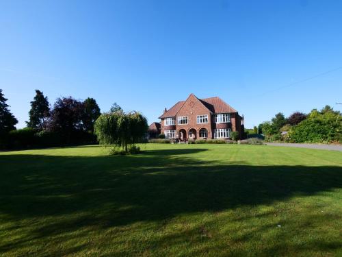a large house on a green field with a tree at Westergate House in York