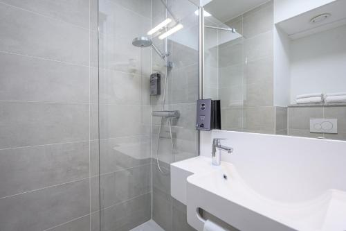 uma casa de banho com um chuveiro, um lavatório e um espelho. em B&B HOTEL Brussels Centre Gare du Midi em Bruxelas