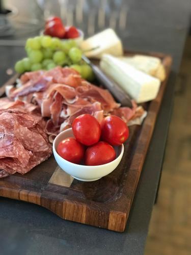 a cutting board with meat and grapes and a bowl of tomatoes at Tree Top Hill - The Old Station House - Båstad Holiday Apartments in Båstad