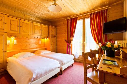 a bedroom with a bed and a desk and a television at Hôtel Le Kandahar in Châtel