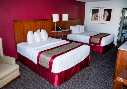 a hotel room with two beds and a chair at Ramada by Wyndham Cedar City in Cedar City