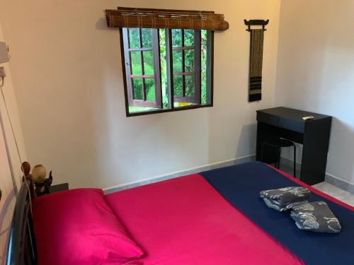 um quarto com uma cama vermelha e uma janela em Lovely Garden Villas em Pantai Cenang