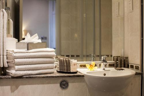 a bathroom with a sink and a pile of towels at Gem Strathmore Hotel in London