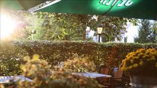 a hedge with tables and chairs and a green umbrella at Hotel Schultheiss Hameln in Hameln