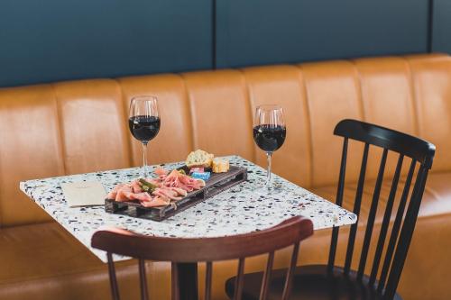 a table with two glasses of wine and a plate of food at Eklo Bordeaux Centre Bastide in Bordeaux