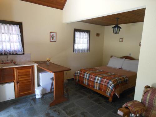 a bedroom with a bed and a desk and a sink at Grunwald Chales in Monte Verde