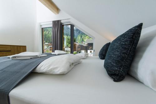 Habitación blanca con cama grande con almohadas en Virgentaler Alp, en Prägraten am Großvenediger