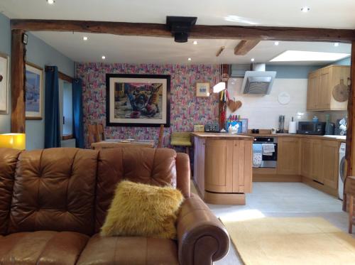 a living room with a couch and a kitchen at Chestnut Lodge in East Dereham