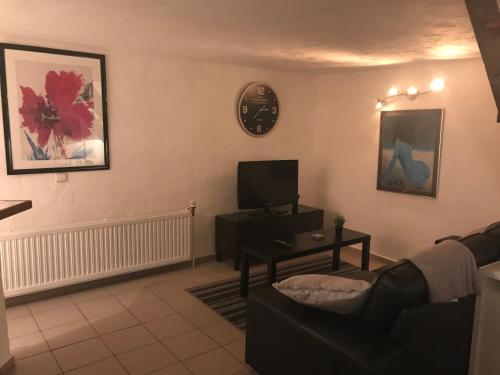een woonkamer met een bank, een tv en een klok bij studio cosy in Gesves