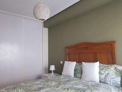 una camera da letto con letto, testiera e cuscini in legno di Calma House a Saragozza