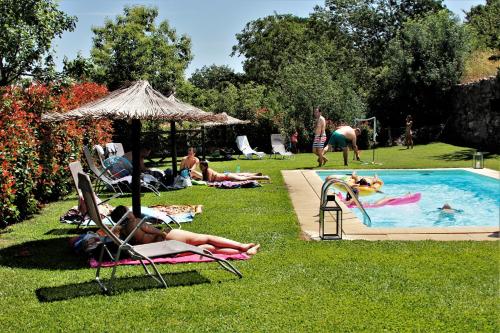 a group of people laying in the grass by a pool at Glamping Hills in Santa Comba de Rossas