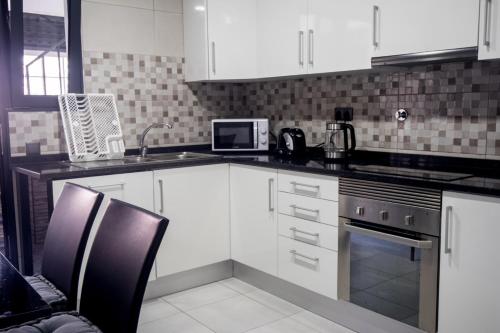 Una cocina con gabinetes blancos, un fregadero y un microondas. en Grannies House, en Machico
