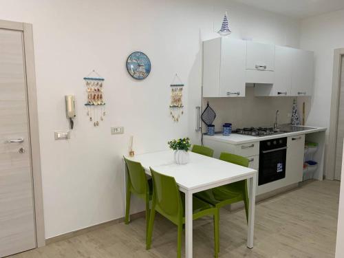 een keuken met een witte tafel en groene stoelen bij Arcorosa Apartment in Cefalù