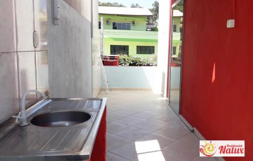 a kitchen with a sink and a red door at Residencial Natux in Bombinhas
