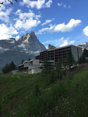 un edificio en una colina con una montaña en el fondo en Complesso i Dadi - Condominio Cielo Alto, en Breuil-Cervinia
