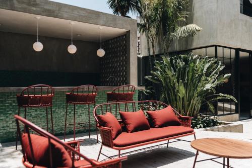 a patio with red chairs and a table and a table and chairs at Casa Ixaya by Barrio México in Guadalajara