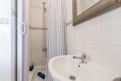 ein weißes Bad mit einem Waschbecken und einer Dusche in der Unterkunft Light Filled Typical Apartment at Alfama, By TimeCooler in Lissabon