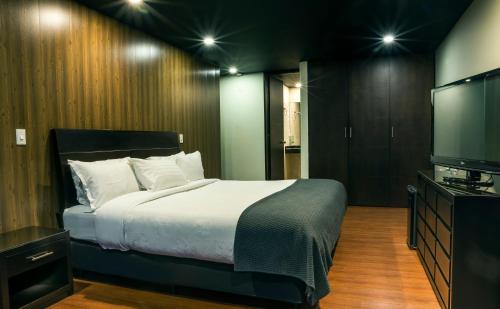 a bedroom with a bed and a dresser at Hotel Santa Barbara Real in Bogotá