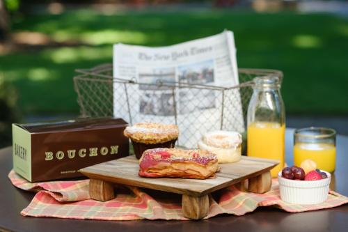 a table with a wooden cutting board with pastries and orange juice at The Cottages of Napa Valley in Napa