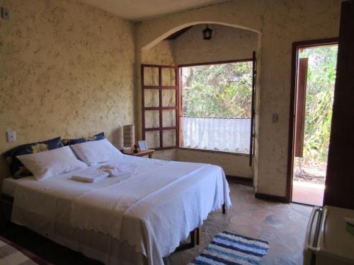 a bedroom with a white bed and a window at D'Elber Pousada in Serra do Cipo
