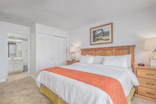 een slaapkamer met een groot bed en een oranje deken bij GetAways at Turtle Reef Club in Jensen Beach