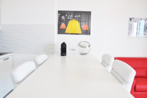 アルゲーロにあるスピンネーカー ホリデイズの白いテーブルと赤いソファが備わる白い部屋