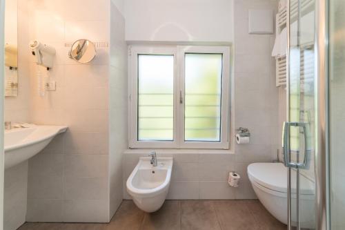 a bathroom with a sink and a toilet and a window at AppartChalet LA RONDULA - 100m from Seceda in Ortisei