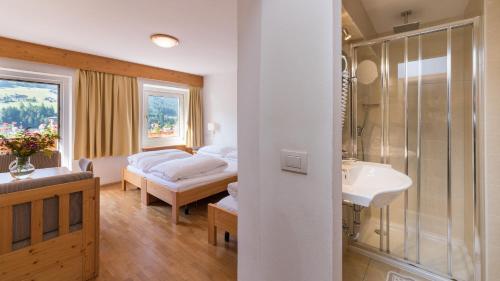 a bedroom with a bed and a sink and a shower at AppartChalet LA RONDULA in Ortisei