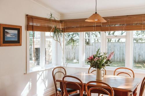 a dining room with a table and chairs and windows at Bow Street Apartments & Cottage in Raglan