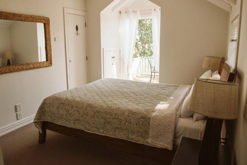 a bedroom with a bed and a mirror and a window at Bow Street Apartments & Cottage in Raglan