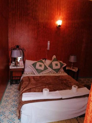a bedroom with a bed with two tables and two lamps at Kasabah Senhaji in Moulay Idriss Zerhoun