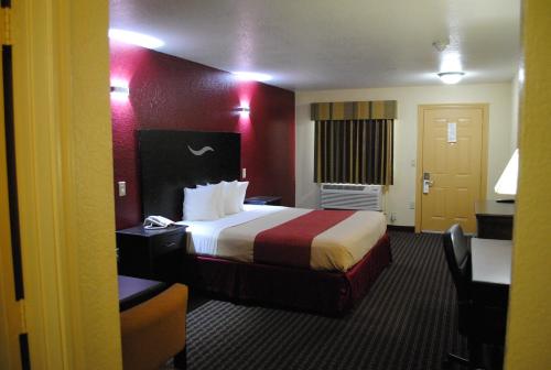 a hotel room with a bed and a desk at Scottish Inns Fort Worth in Fort Worth