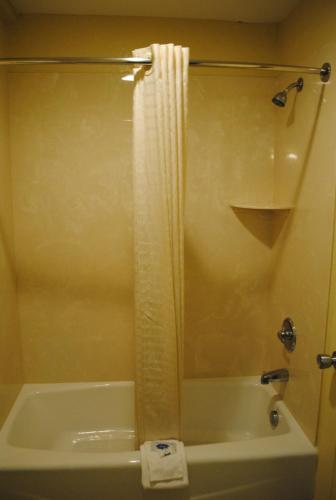a bathroom with a tub and a shower with a shower curtain at Scottish Inns Fort Worth in Fort Worth
