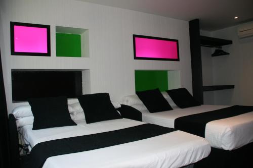 a room with three beds with pink and green screens at Hotel Indiana in Pinto