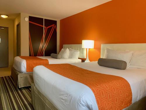 two beds in a hotel room with orange walls at Howard Johnson by Wyndham Winnipeg West in Winnipeg