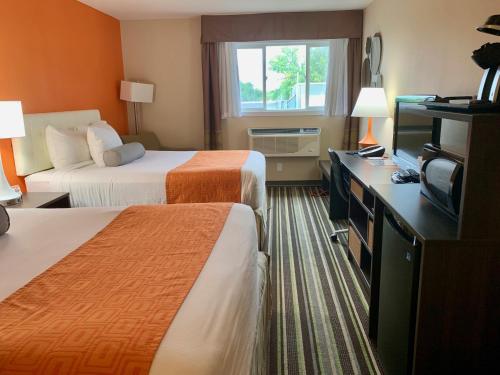 a hotel room with two beds and a television at Howard Johnson by Wyndham Winnipeg West in Winnipeg