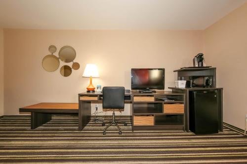 a hotel room with a desk and a television at Howard Johnson by Wyndham Winnipeg West in Winnipeg