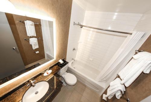 a bathroom with a sink and a toilet and a tub at Howard Johnson by Wyndham Winnipeg West in Winnipeg