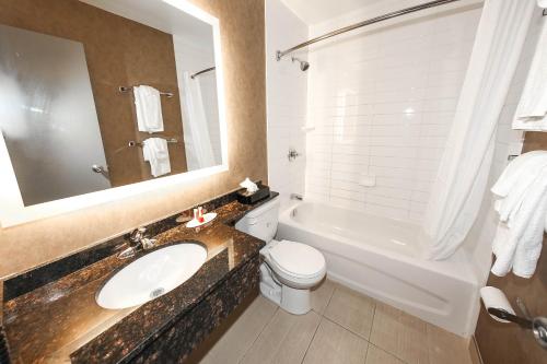 a bathroom with a sink and a toilet and a tub at Howard Johnson by Wyndham Winnipeg West in Winnipeg