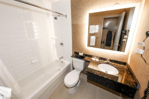 a bathroom with a sink and a toilet and a bath tub at Howard Johnson by Wyndham Winnipeg West in Winnipeg
