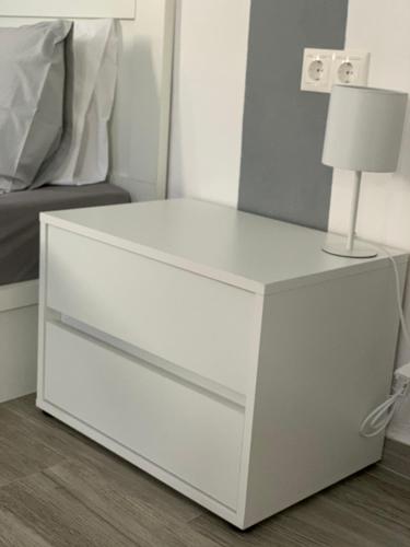 a white dresser with a lamp on it next to a bed at Dominik apartment in Patmos